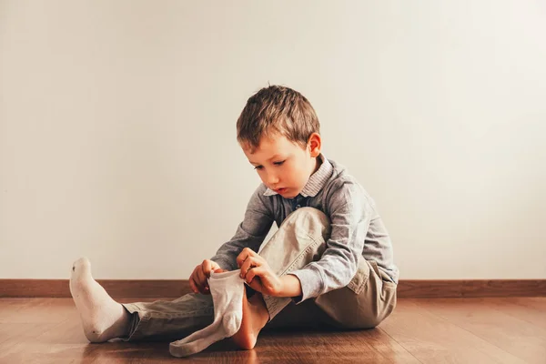 Child with lots of independence sitting on the floor putting on Stock Picture