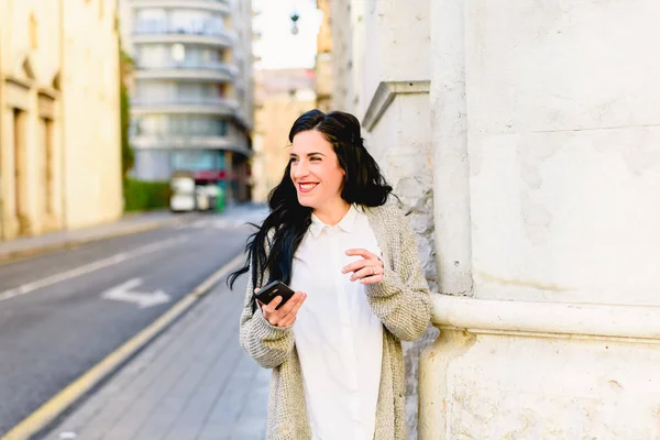 Young woman laughing holding her smartphone, happy to receive go — Stock Photo, Image