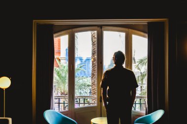 Büyük bir pencerenin önünde ofisinde girişimci adam.