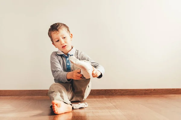 Niño con mucha independencia sentado en el suelo poniéndose — Foto de Stock