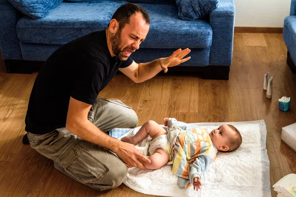 Novice father changing the stinking diaper of a baby with a gest — Stock Photo, Image