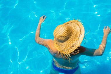 Kadın rahat ve dinlenmiş şapka ile bir havuzda.