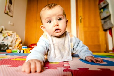 Kamera merakla izliyor yerde yatan bebek.
