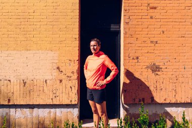 Turuncu bir duvarın önünde poz olgun sporcu kadın.