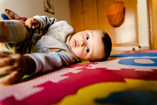 Baby lying on the floor watching the camera with curiosity. — Stock Photo, Image