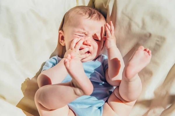 Baby lying in the sun angry and crying calling his parents.