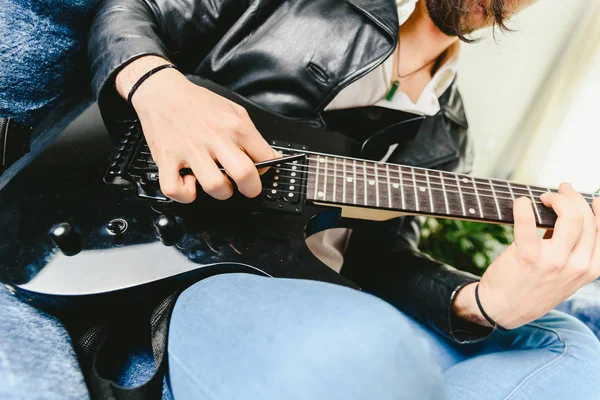 Joven practicando con su guitarra eléctrica en el sofá de su — Foto de Stock