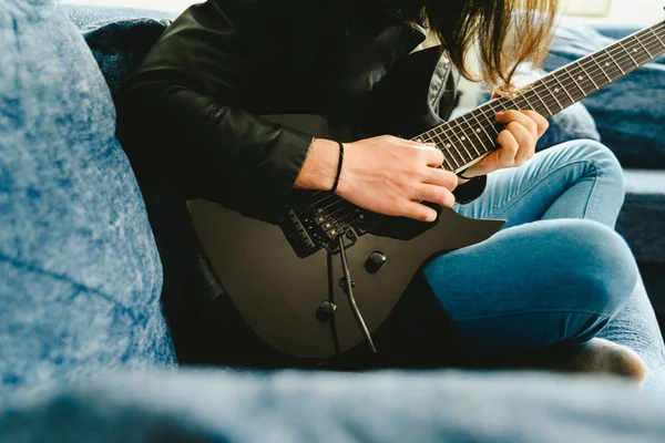 Jovem tocando sua guitarra elétrica preta sentado e desfrutando — Fotografia de Stock