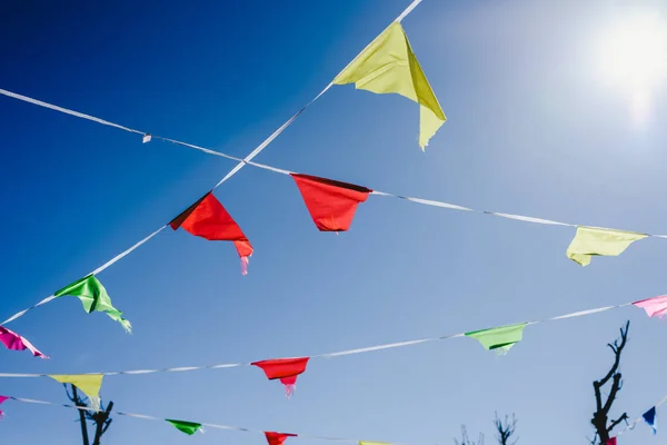 Colored flags against the sun waving in the wind at an outdoor p