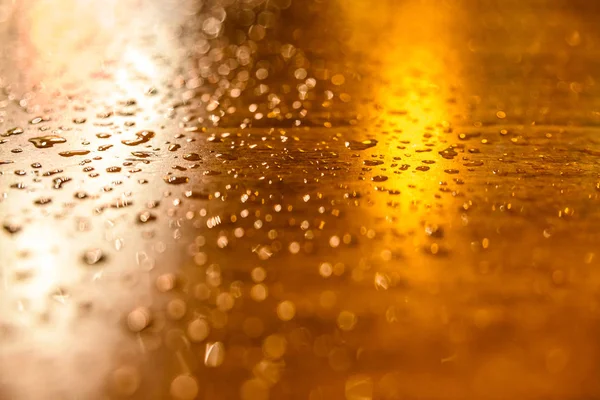 Gotas de lluvia sobre una mesa de madera iluminada por farolas una — Foto de Stock