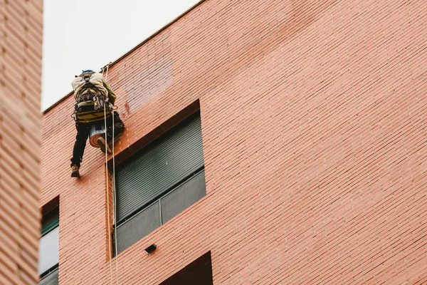Pittore appollaiato sulle pareti di un edificio con corde . — Foto Stock