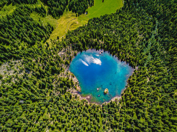 Aerial photo of a blue lake between alpine mountains.