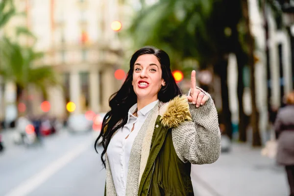 Middle-aged woman hailing a taxi with her hand raised in the str — Stock Photo, Image