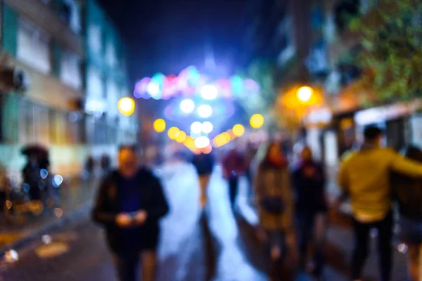 Scena notturna urbana con persone che camminano fuori fuoco con colori — Foto Stock