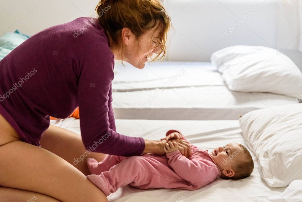 Single mother waking up her baby lying on the bed making gesture