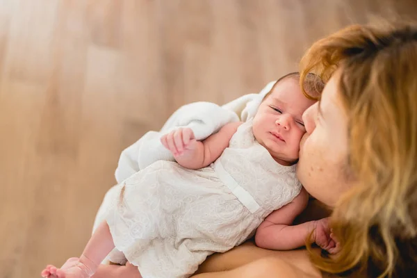 Mother kissing her newborn daughter after breastfeeding