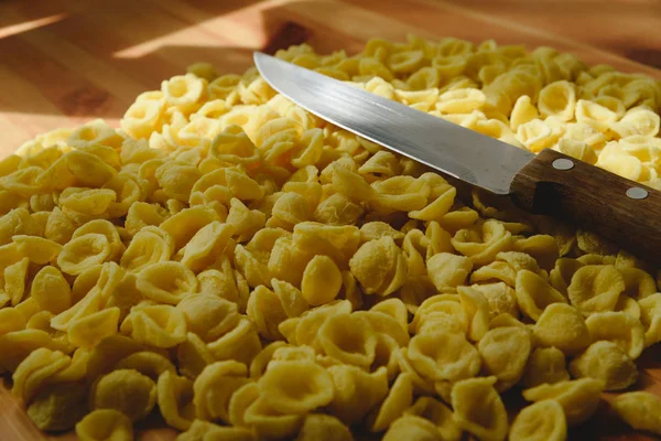 Orecchiette, pâtes de semoule de blé italien, sur une table et un couteau — Photo