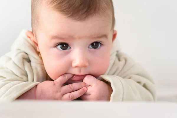 Portrait of an adorable smiling baby biting her own fingers putt — Stock Photo, Image