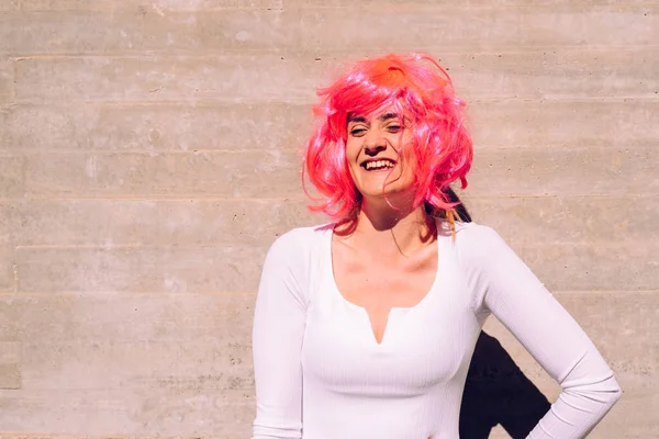 Slender and ugly woman with colorful wig posing ridiculously.