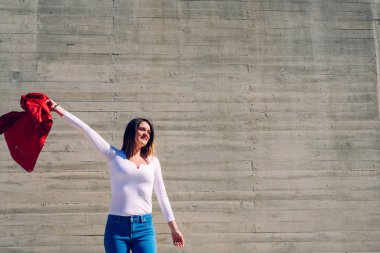 Gri arka plan ile onu kırmızı ceket sallayarak genç kadın.