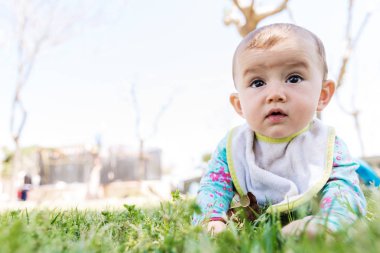 Bebek çimenlerin üzerinde yüzüstü yatarak başını kaldırıyor..