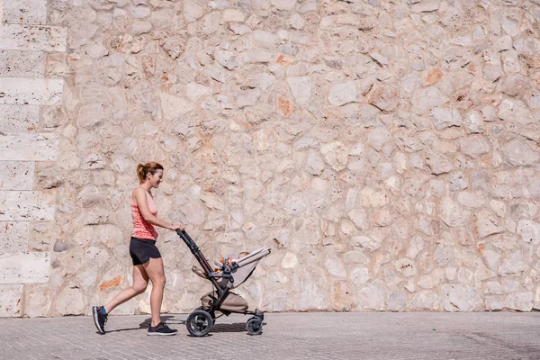 Kadın, anne bebek arabası iterek Fitness yapıyor. — Stok fotoğraf