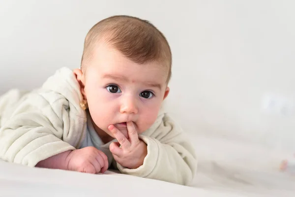 Portrait of an adorable smiling baby biting her own fingers putt — Stock Photo, Image