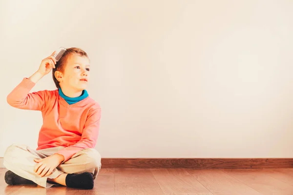 Niño sentado en el suelo de su casa se ve guapo mientras h — Foto de Stock