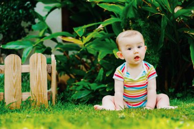 Bebek sevimli bir gülümseme ile yalınayak çim üzerinde oturan.