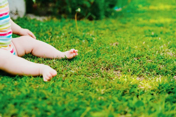 Nakna fötter av en bebis sitter på gräset, med massor av gratis SP — Stockfoto