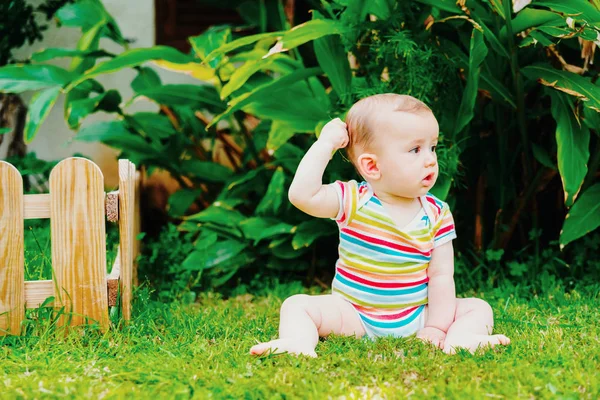 Yalınayak bebek çimenlerin üzerinde otururken başını kaşıyan düşünce