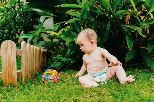 Bayi duduk di halaman bertelanjang kaki bermain dengan mainan berwarna-warni untuk — Stok Foto