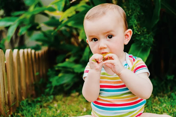 Bebé poniendo en su boca una flor de un jardín, concepto de dange — Foto de Stock