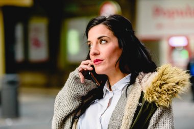 Orta yaşlı kadın, cep telefonundan telefon görüşmesi yapıyor.