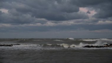 Wind storm in the sea, waves hitting rocks in the rain clouds