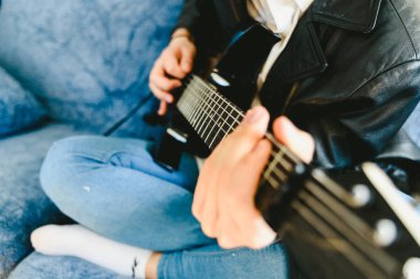 Genç adam onun kanepede onun elektro gitar ile pratik