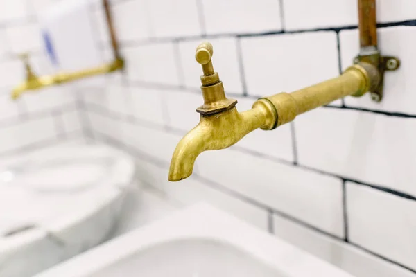 Retro faucet gilded hot water with metal pipes in sight. — Stock Photo, Image