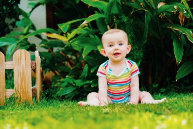 Bebek sevimli bir gülümseme ile yalınayak çim üzerinde oturan.