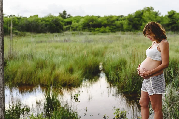 Pregnant woman relaxing looking at the landscape of a lake. — Stock Photo, Image