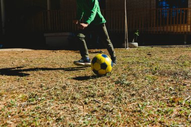 Çocuğun evinin bahçesinde bir futbol topu ile oynayan