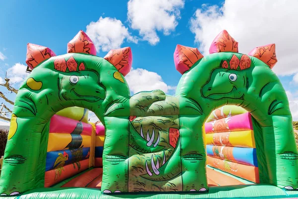 Bouncy castle in the shape of dinosaurs in a children\'s playgrou