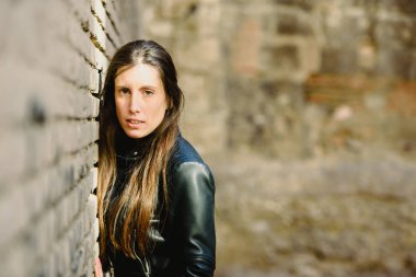 Kızgın ve dalgın yetişkin genç kadın bir tuğla yaslanmış baş