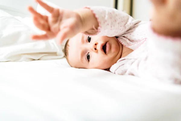 6 month old baby lying on his white bed playing with his hands. — Stock Photo, Image