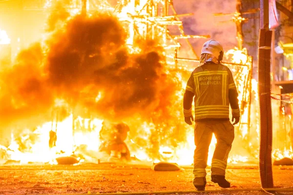 Silhouette eines Feuerwehrmannes, der versucht, ein Feuer in einer Straße unter Kontrolle zu bringen — Stockfoto