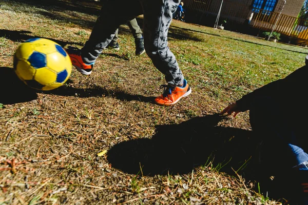 Niños persiguiendo una vieja pelota de fútbol en un partido amistoso en Summe — Foto de Stock