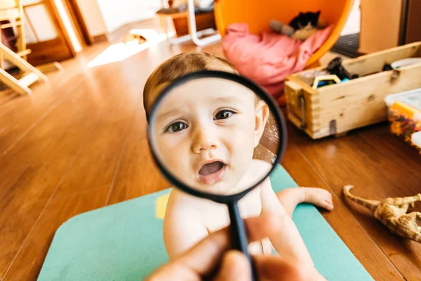Μωρό πρόσωπο παίζοντας με ένα μεγεθυντικό φακό, που κάνει ένα f — Φωτογραφία Αρχείου