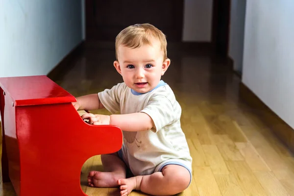 Sonriente bebé tocando un piano de juguete mientras aprende música . — Foto de Stock