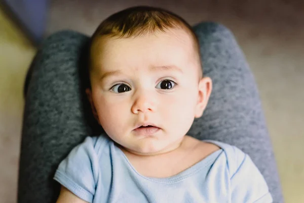 Retrato de la cara redonda de un bebé en las piernas de su madre . — Foto de Stock