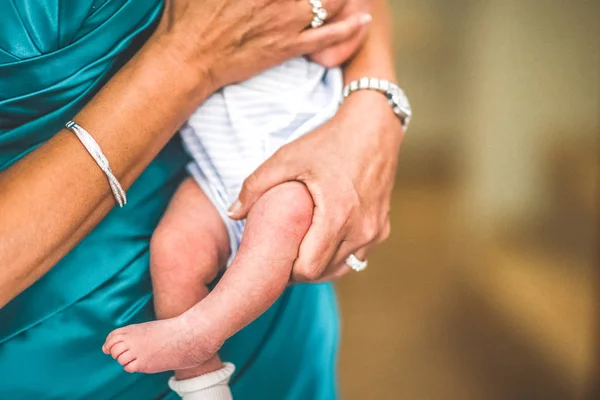 Säuglingsbeine von zerbrechlichem Aussehen, getragen von den Armen der Mutter. — Stockfoto