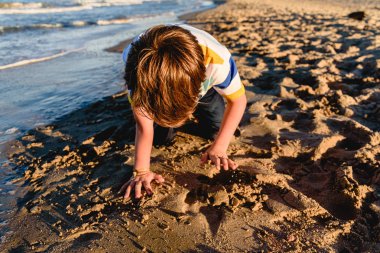 Çocuk onun elbis sırasında sahilde çalıştırdıktan sonra yorgun diz çökmüş